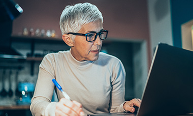 person writing grant on laptop